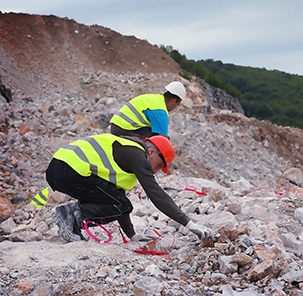 Explosiveprogress workers in work clothes and protective helmets preparing to carry out a drill and blast operation.