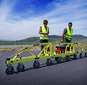 Road Company employees with reflective vests testing a pavement testing device on a paved road.