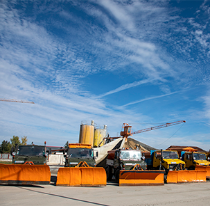 Bekastroy construction equipment, including trucks and bulldozers with snow plows, on a construction site.