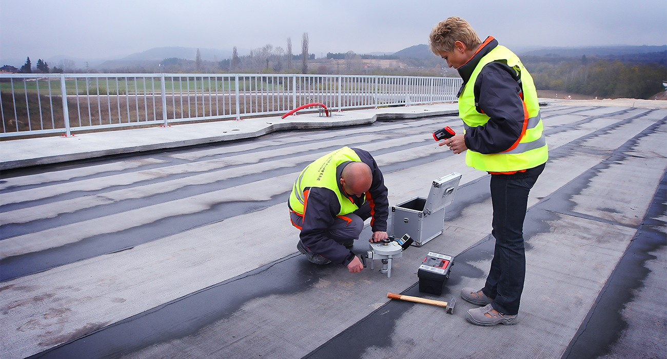 Employees from the Road Company testing the quality of the road surface with the help of equipment.