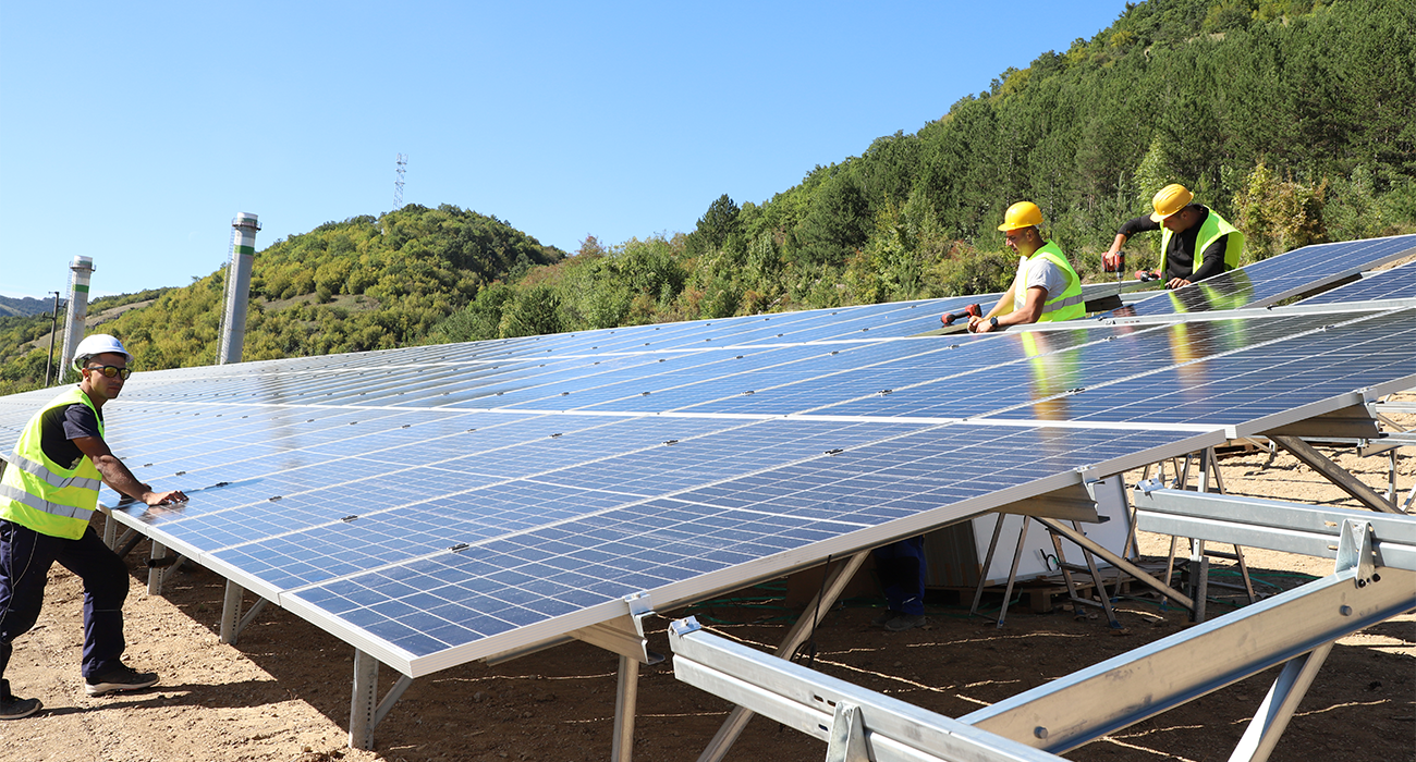Workers in protective clothing and helmets installing solar panels.