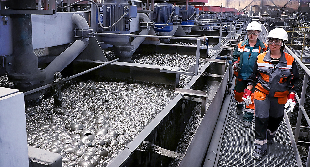 Employees from Ellatzite Med in work clothes and safety helmets in a production workshop near containers of bubbling material.