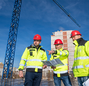 Geostroy employees at a construction site wearing reflective work clothes and safety helmets.