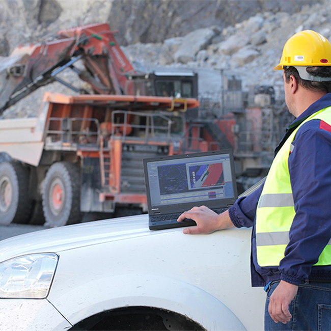 An Ellatzite-Med employee wearing a safety helmet and reflective vest operating the Dispatch® software, on the job site.